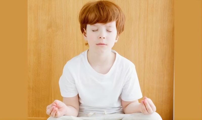 Bambino che medita seduto in tranquillità durante una pratica di consapevolezza
