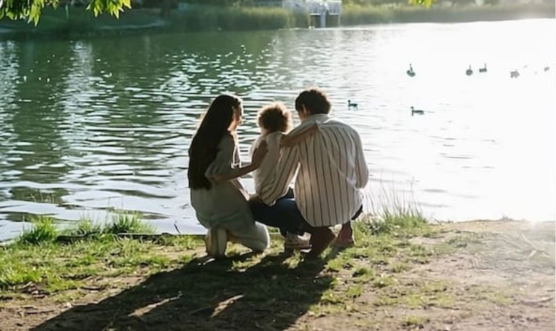 Genitori e bambino in riva al lago, immagine che rappresenta la coregolazione emotiva