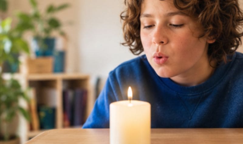 Bambino che soffia su una candela durante un esercizio di respirazione per favorire la calma e la consapevolezza del respiro